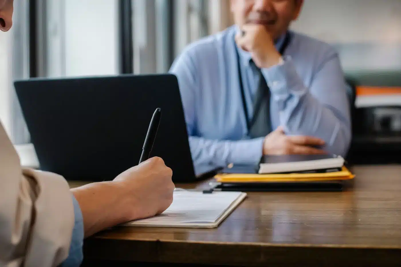 Dos personas firmando un contrato sobre un escritorio